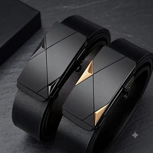 May include: Two black belts with textured straps and rectangular buckles. One buckle is solid black with geometric lines, while the other features black surfaces accented with two gold-toned triangular details on the sides of the buckle face.