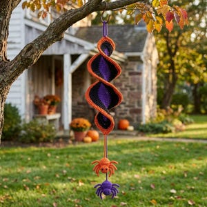May include: A spiral-shaped crochet hanging decoration featuring alternating bands of black, purple, and orange yarn. Two small crocheted spiders, one orange and one purple, are suspended from the bottom of the spiral structure by a yarn cord.