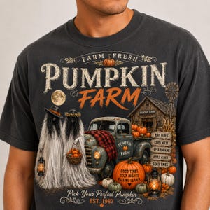 May include: A charcoal gray t-shirt featuring a graphic print with the text "FARM FRESH PUMPKIN FARM" and "EST. 1987". The design includes two ghost-like figures, a vintage truck, a barn, pumpkins, lanterns, and a full moon in a rustic style.