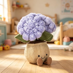 Pode incluir: Um brinquedo de pelúcia em forma de planta em vaso com uma base redonda de tecido texturizado bege, apresentando um rosto sorridente costurado e dois pés pequenos. O topo consiste em cachos de flores fofos, roxo-claros, com pontos brancos e folhas verdes.