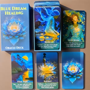 Può includere: Un mazzo di carte oracolo Blue Dream Healing con una scatola blu decorata con un'illustrazione di loto e cinque carte. Le carte mostrano illustrazioni di una figura, una persona, un paesaggio e fiori di loto con testo tra cui Awake, Lucid Dream, Silent Night e Radiance.