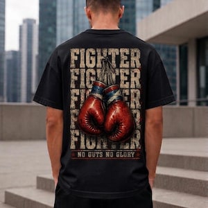 May include: A black t-shirt featuring a graphic on the back with a pair of red boxing gloves hanging by their laces. The background of the graphic displays the word FIGHTER repeated in a distressed font, with the text NO GUTS NO GLORY at the bottom.