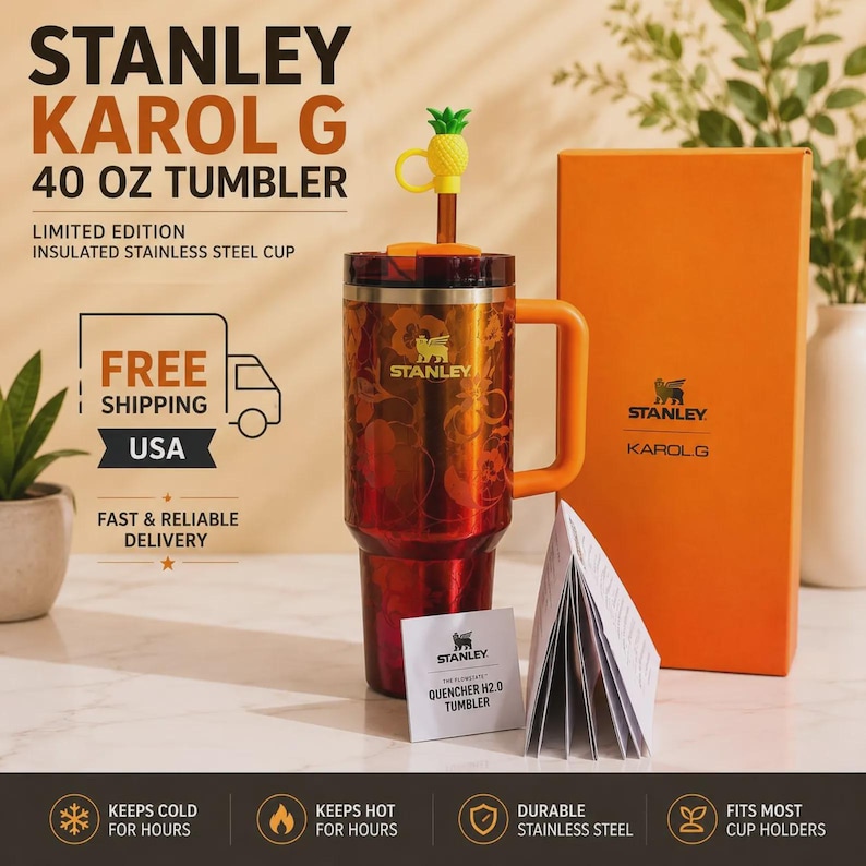 May include: A 40 oz Stanley Karol G insulated stainless steel tumbler with a red and orange floral pattern, an orange handle, and a straw topped with a yellow pineapple charm. The set includes an orange box and a white product information booklet.