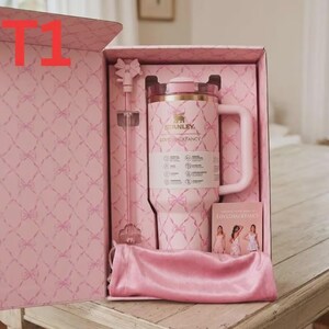 May include: A pink Stanley tumbler with a bow pattern, a matching bow-topped straw, and a pink satin pouch inside a branded gift box. The tumbler features the Stanley and LoveShackFancy logos, a handle, and a clear lid, presented in a box with a bow print.