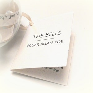 May include: A white card with black text that reads "THE BELLS" and "EDGAR ALLAN POE".