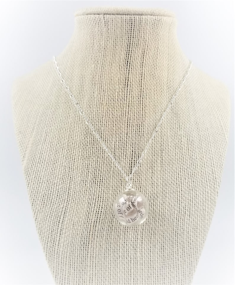 Peut inclure: Un collier en argent avec un pendentif rond sur lequel est inscrit le texte "She is up off of her knees and her head is held high".