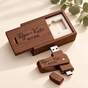 Könnte beinhalten: Eine dunkelbraune Holzschiebebox mit weißem Schaumstoffeinsatz und einem passenden USB-Stick aus Holz. Beide Artikel sind mit dem Text Ryan + Kate und dem Datum 17.10.2026 graviert. Der USB-Stick verfügt über eine Schwenkkappe und einen Metallanschluss.