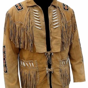 May include: A tan suede jacket featuring long fringe detailing on the chest and pockets. The garment is adorned with white bone-style beads and decorative patches with black, red, and yellow geometric patterns on the shoulders and sleeves.