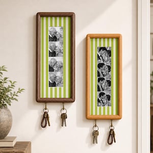 May include: Two rectangular wall-mounted wooden frames with light green and white vertical striped backings. Each frame displays a vertical strip of four black and white photographs of couples. Two metal hooks at the bottom of each frame hold keys.
