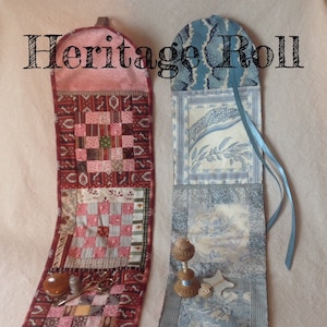 May include: Two fabric Heritage Roll organisers with the text Heritage Roll and Collector With a Needle (c) 2018. The left roll features red and pink patchwork patterns with a thimble and scissors. The right roll has blue toile patterns with a wooden spool.
