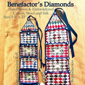 May include: A pair of hand-sewn and embroidered fabric needle cases, one antique and one reproduction. Both are made of cotton, wool, and silk and feature a red, white, and blue diamond pattern. The antique case has a small, embroidered pouch at the bottom, while the reproduction case has a heart-shaped pouch with the text "DCR 2021". Both cases are 5.5 inches wide and 23 inches long.