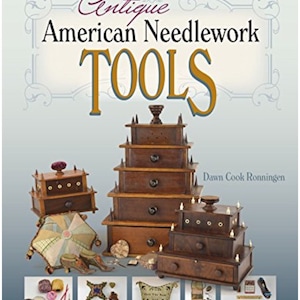 May include: Antique American needlework tools, including a wooden sewing box with multiple drawers, a small wooden box with a drawer, a needlepoint pillow, and a variety of other tools. The book cover reads "Antique American Needlework Tools" by Dawn Cook Ronningen.