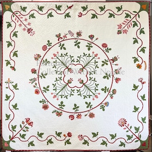 May include: A square white quilt featuring a central circular vine motif with pink and red floral appliqués. The border displays a continuous red vine with green leaves and flowers. The text Pattern By Collector With A Needle is visible.