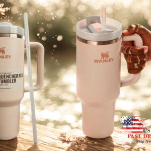 May include: A pale pink Stanley Flowstate Quencher H2.0 tumbler with a handle, a white lid, and a matching straw. The tumbler features the Stanley logo and text reading The Flowstate Quencher H2.0 Tumbler 40 oz 1.18 L on a product label.