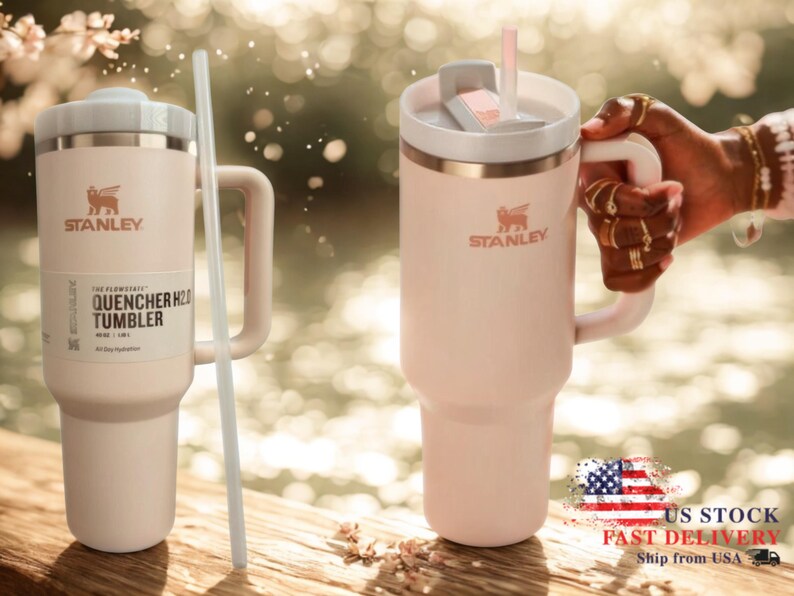 May include: A pale pink Stanley Flowstate Quencher H2.0 tumbler with a handle, a white lid, and a matching straw. The tumbler features the Stanley logo and text reading The Flowstate Quencher H2.0 Tumbler 40 oz 1.18 L on a product label.