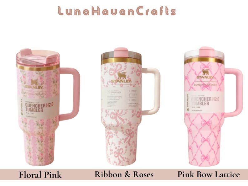 May include: Three Stanley Quencher H2.0 tumblers with handles and lids. The first features a pink floral pattern, the second a pink ribbon and rose design, and the third a pink bow lattice pattern. Each tumbler displays the Stanley logo and branding.