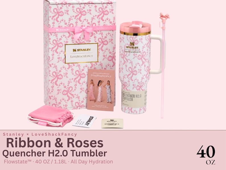 May include: A Stanley x LoveShackFancy 40 oz Quencher H2.0 tumbler featuring a white and pink ribbon and rose pattern, a matching gift box, a pink straw with a bow topper, a small pink pouch, and a promotional card showing three models in dresses.