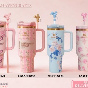 May include: Four Stanley Quencher H2.0 tumblers with handles and straws. The first is pink with floral patterns, the second is pink with ribbon rose designs, the third is light blue with floral prints, and the fourth is white with pink rose patterns.