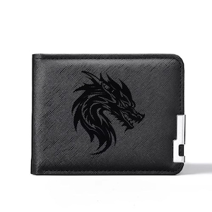 May include: A black bifold wallet with a textured surface featuring a dark, embossed dragon head graphic on the front. The wallet includes a silver-toned metal accent piece attached to the lower right corner, providing a contrast to the black material.