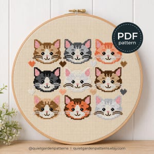 Pode incluir: Um padrão de ponto cruz num bastidor de madeira com nove rostos de gato em várias cores, incluindo castanho, cinzento, laranja, preto e branco. Pequenos corações estão intercalados entre os gatos. O texto diz PDF pattern.
