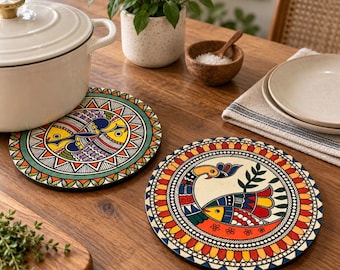 May include: Two round wooden trivets featuring vibrant, hand-painted folk art designs. One trivet displays a stylized fish motif in yellow, blue, and red, while the other depicts a peacock with colorful plumage. Both have intricate geometric borders.