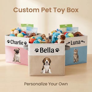 May include: Three square fabric storage bins labeled Custom Pet Toy Box and Personalize Your Own. Each bin features a pet name, paw or fish icons, and a photo of a dog or cat. The bins are pink, beige, and blue, filled with various pet toys.