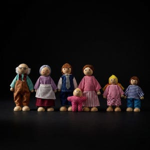 Puede incluir: Un conjunto de seis muñecos de madera que representan una familia, incluyendo dos adultos con cabello gris, dos padres, un bebé pequeño con un traje rosa de lunares y dos niños, todos vestidos con ropa de tela colorida y rasgos faciales pintados.