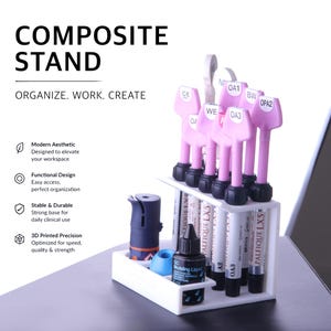 Peut inclure: Un support en plastique blanc à deux niveaux contenant plusieurs seringues composites dentaires avec des poignées roses et des étiquettes incluant CE, OA1, BW, OPA2, OA3 et WE. Un petit flacon noir étiqueté GC Modeling Liquid et un outil bleu sont sur la base.