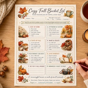May include: A printed Cozy Fall Bucket List checklist featuring eight sections with autumn-themed illustrations including pumpkins, leaves, mugs, and a camera. The paper includes text prompts for seasonal activities and blank lines for writing, with a maroon pen.