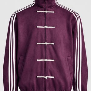 May include: A deep purple track jacket featuring a high collar, a full-length front zipper, and five white toggle closures. The sleeves are accented with three white stripes running from the collar to the cuffs, and the hem and cuffs are ribbed.