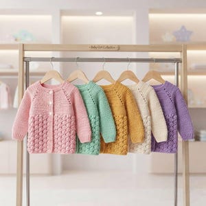 May include: Five long-sleeved crochet cardigans hanging on wooden hangers on a rack. The cardigans are in pink, mint green, mustard yellow, cream, and lavender. Each features a button-up front, a textured stitch pattern, and a round neckline.