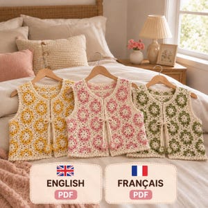 Peut inclure: Trois gilets sans manches en crochet suspendus sur des cintres en bois. Chaque gilet présente un motif floral répété en carrés de grand-mère, couleur crème avec des centres jaunes, roses ou verts. Fermeture à nouer avec petites fleurs.