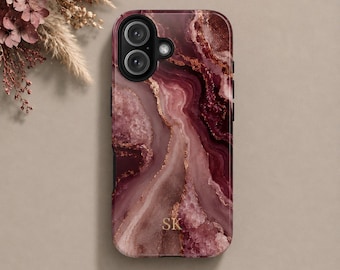 May include: A phone case featuring a deep burgundy and mauve marbled pattern with gold-toned veining and the gold-lettered initials SK centered near the bottom. The case includes a black camera module and is labeled with the text MAGSAFE.