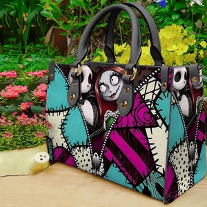 Puede incluir: Un bolso de mano estructurado con un estampado gr&aacute;fico de Jack Skellington y Sally de Pesadilla antes de Navidad. El dise&ntilde;o incluye un patr&oacute;n de parches en color turquesa, magenta y blanco con detalles de costuras negras y dos asas grises.