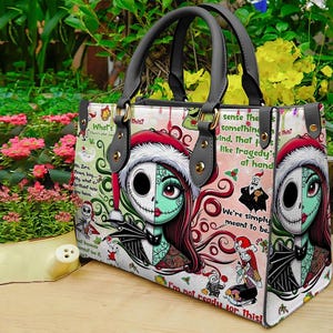 May include: A rectangular handbag with two grey handles featuring a graphic print of characters from The Nightmare Before Christmas. The design includes Sally and Jack Skellington, red Santa hats, holly, and text snippets like We're simply meant to be.