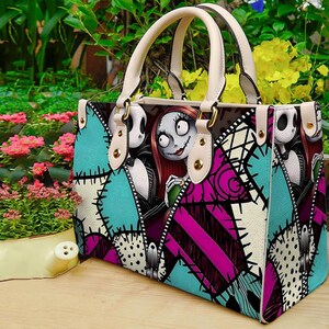 Puede incluir: Un bolso estructurado con un estampado gr&aacute;fico de Jack Skellington y Sally de Pesadilla antes de Navidad. El dise&ntilde;o incluye un patr&oacute;n de patchwork en turquesa, magenta y blanco con detalles de costuras negras y dos asas de color crema.