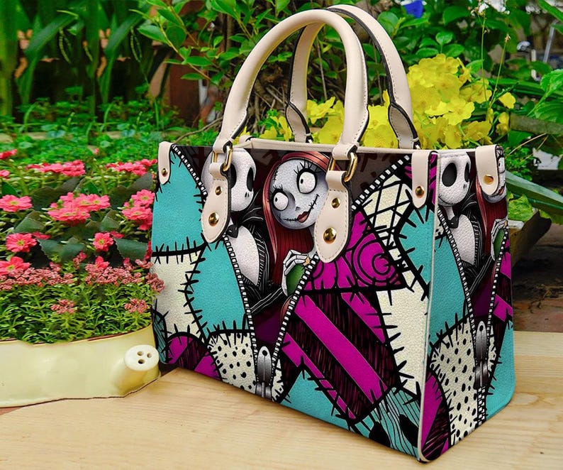Puede incluir: Un bolso estructurado con un estampado gr&aacute;fico de Jack Skellington y Sally de Pesadilla antes de Navidad. El dise&ntilde;o incluye un patr&oacute;n de patchwork en turquesa, magenta y blanco con detalles de costuras negras y dos asas de color crema.