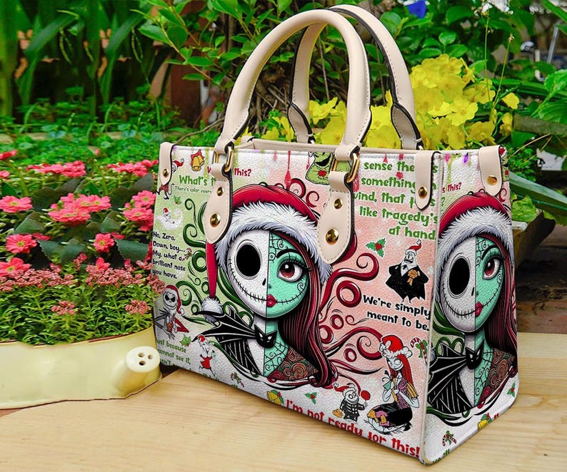 May include: A structured handbag featuring a split-face character design of a skeleton and a stitched doll wearing a Santa hat. The bag includes cream-colored handles, gold-tone hardware, and a repeating pattern of holiday-themed text and graphics.