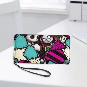 Puede incluir: Una cartera rectangular con cremallera que presenta un estampado gr&aacute;fico de Jack Skellington y Sally de Pesadilla antes de Navidad. El dise&ntilde;o incluye un patr&oacute;n de parches en tonos turquesa, rosa y crema con detalles de costuras negras.