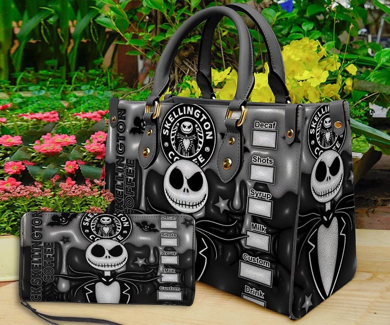 Op de afbeelding: Een grijze en zwarte handtas en bijpassende portemonnee met een Jack Skellington-afbeelding, een rond Skellington Coffee-logo en een checklist-ontwerp met de labels Decaf, Shots, Syrup, Milk, Custom en Drink op het oppervlak gedrukt.