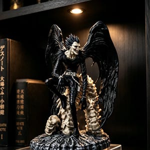 May include: A detailed figurine of a tall, slender, black-winged humanoid character with spiky hair and a wide, toothy grin. The figure wears a black outfit with a silver belt and chain, perched atop a textured, bone-coloured, skeletal-like base.