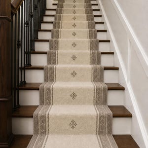 May include: A staircase featuring a beige carpet runner with a repeating diamond-shaped pattern and dark brown side borders. The stairs have dark wood treads and white risers, complemented by a dark wood handrail with black metal balusters.