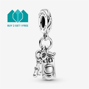 Peut inclure: Un charm en argent composé d'une clé pendante et d'un personnage horloge rectangulaire avec un visage. La bélière supérieure est gravée du mot Pandora et S925. Le design est en argent métallique avec des détails en relief sur l'horloge et la clé.