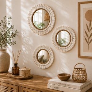 May include: Three circular wall mirrors featuring cream-colored macrame fringe borders and inner rope detailing. The mirrors are arranged in a cluster on a wall, showcasing reflective glass surfaces surrounded by textured, knotted fiber accents.