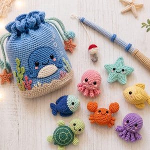 May include: A blue crochet drawstring bag featuring a whale applique, accompanied by a crochet fishing rod and several small stuffed sea creatures including a pink octopus, a green starfish, a yellow fish, a blue fish, an orange crab, and a purple octopus.