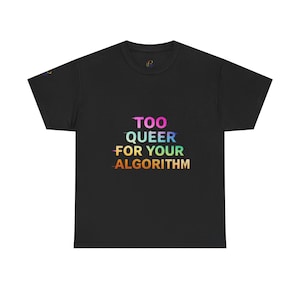 May include: A black short-sleeve t-shirt featuring the text "TOO QUEER FOR YOUR ALGORITHM" printed in a horizontal gradient of rainbow colors. The lettering has a slight glitch effect, and a small logo is visible on the inner neck label.