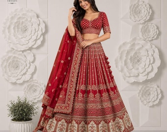 Puede incluir: Un conjunto de lehenga choli rojo que incluye una blusa corta y una falda larga con intrincados bordados dorados, lentejuelas y un dupatta transparente a juego con borde decorativo y detallados patrones florales en la tela.
