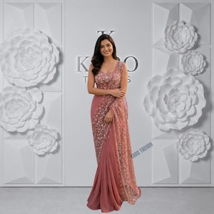 May include: A dusty rose saree featuring intricate white floral embroidery across the bodice and the pallu. The garment has a sleeveless fitted top and a flowing skirt section with a sheer overlay. The text KARO TRENDS is visible in the background.