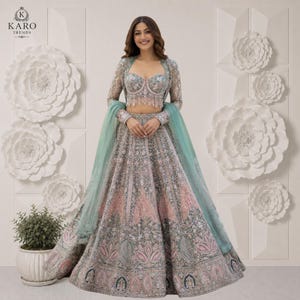 Puede incluir: Un lehenga choli multicolor que presenta una blusa estilo bustier con intrincados bordados y pedrer&iacute;a, combinado con una falda voluminosa hasta el suelo adornada con patrones florales en tonos verde salvia, rosa y plata, y un dupatta transparente.