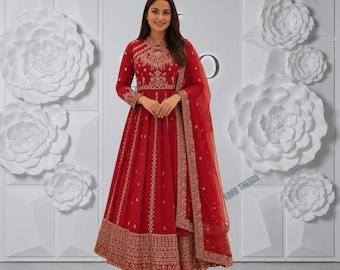Puede incluir: Un vestido rojo largo hasta el suelo con mangas largas, escote tipo cerradura y bordados dorados intrincados en el corpiño, la cintura y el dobladillo. Incluye una dupatta roja transparente a juego con ribete dorado sobre un hombro.